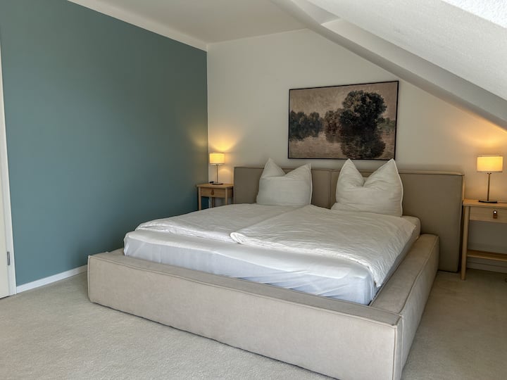 Gemütliches Schlafzimmer mit großem Kingsize Boxspringbett 1,80x2,00 Meter, stilvoller Wandgestaltung und warmem Licht – ideal zum Entspannen nach einem erlebnisreichen Tag.
