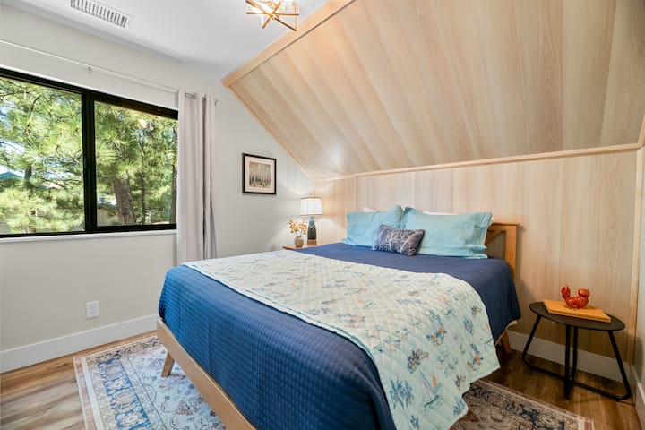This upper level bedroom has 1 queen bed, a 43” Samsung TV with Roku, hardwood floor, and a closet.