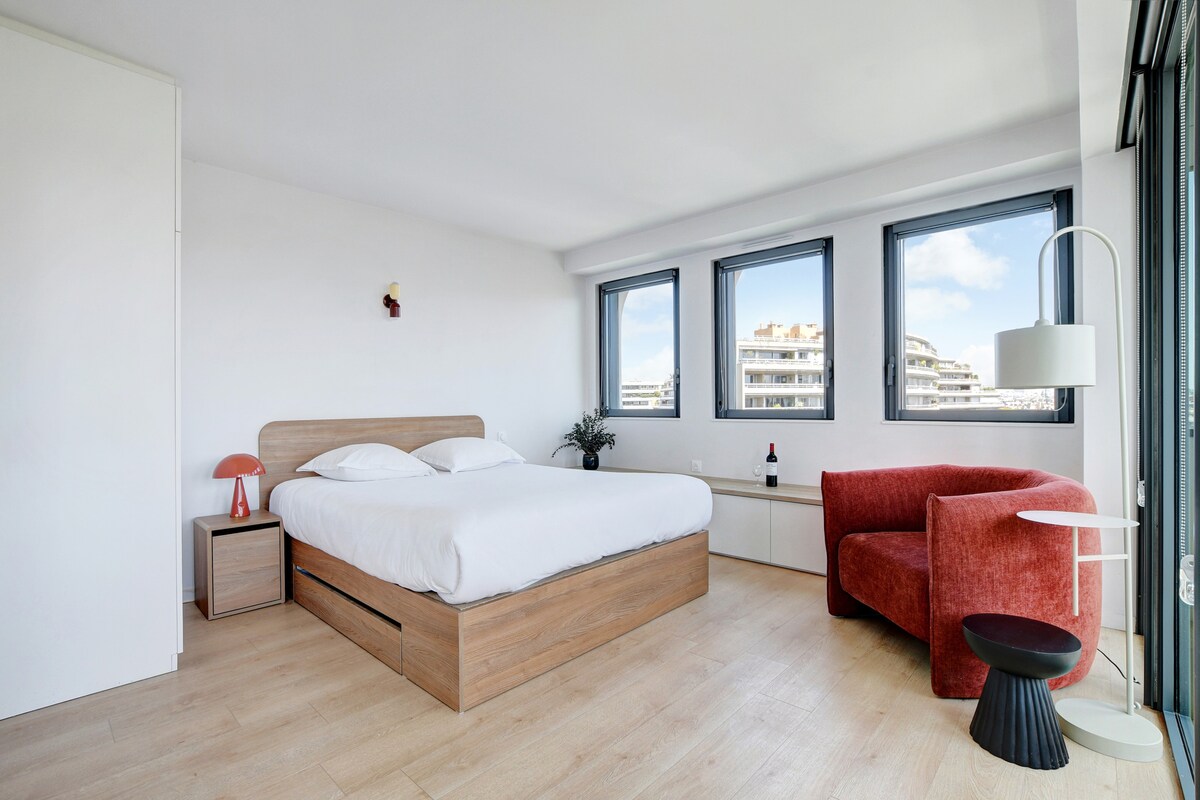 Sala de estar luminosa con una cama tamaño queen, mesa de comedor y pequeña cocina 