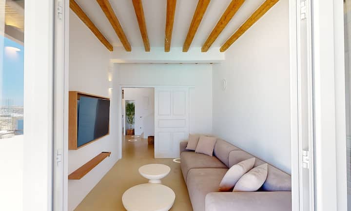 חדר טלוויזיה בקומת הקרקע עם גישה ישירה לאזור האוכל והמנגל בחוץ — יכול לשמש גם כחדר שינה יחיד.