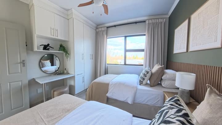 Cómoda habitación con 2 camas individuales extra largas, sábanas y toallas 100 % de algodón. Esta habitación también incluye un tocador con espejo y secador de pelo, perchero, calefacción, ventilador de techo, armarios empotrados con perchas y cortinas 100 % opacas.