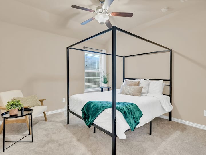 חדר שינה משני מסוגנן עם מיטת קווין סייז עם חופה ומאוורר תקרה לנוחות נוספת.