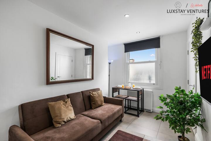 Prostrani dnevni boravak s udobnim kaučem, velikim ogledalom, velikim prozorom za puno prirodnog svjetla i blagovaonskim stolom za dvoje savršenim za opuštanje ili uživanje u mirnom obroku.