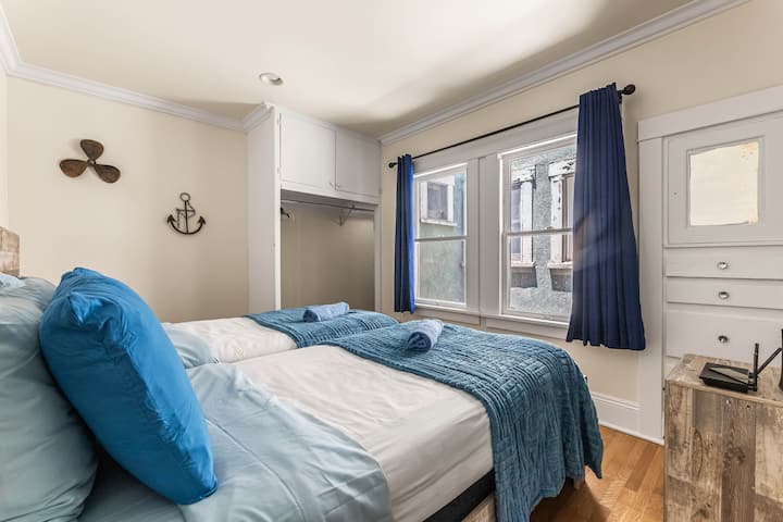 A cozy second bedroom featuring 2 single beds with matching linens, ideal for guests or kids. A spacious dresser and built-in closet provide ample clothing storage. Soft lighting and a neutral palette create a warm, comfortable, and organized space