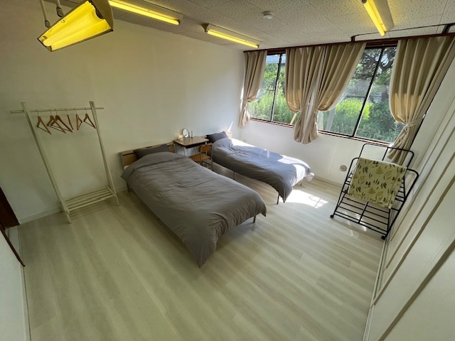 Es un dormitorio.
Hay dos enchufes junto a la almohada y una lámpara, un espejo y una linterna en la mesita de noche.
Hay perchas y futones en la habitación.