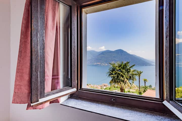 Dirisha linafunguka kwenye mwonekano wa kupendeza wa ziwa na mitende. Panorama ya ndoto kwa ajili ya kuamka kwako.