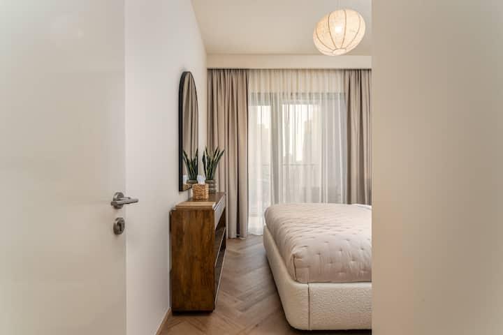 ห้องนอนที่มีสไตล์พร้อมเตียงนอนสบาย เครื่องเรือนทันสมัย และหน้าต่างสูงจากพื้นจรดเพดานที่มองเห็นวิวเมืองที่สวยงามทั้งกลางวันและกลางคืน
