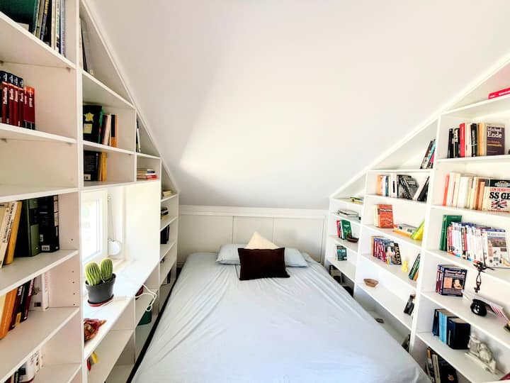 מיטה נוחה ממוקמת בין ספרים, מיטת קינג סייז גדולה פרימיום של Emma בגודל 180x200 ס"מ, עם גישה לגג.