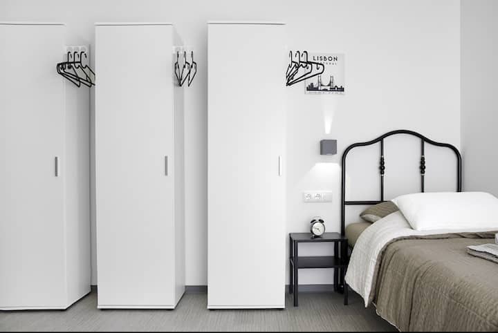 חדר שינה מרוהט מודרני עם שתי מיטות יחיד נוחות, שידות ליד המיטה ותאורה אווירית. אידיאלי לעמיתים או חברים. מצעים איכותיים, מלתחה ואווירה שקטה לשינה טובה.