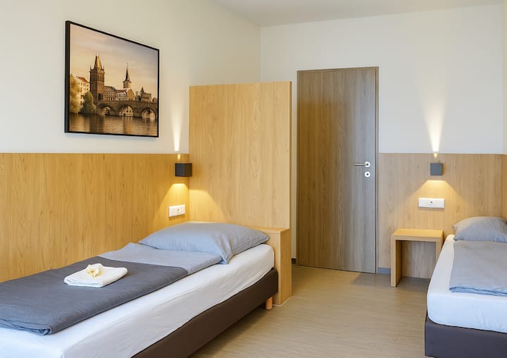 غرفة نوم مفروشة حديثًا مع 3 أسرّة مفردة مريحة وطاولات بجانب السرير وإضاءة في الغلاف الجوي. مثالي للفرق يوم الاثنين. توجد أسرّة عالية الجودة ومساحة تخزين واسعة.