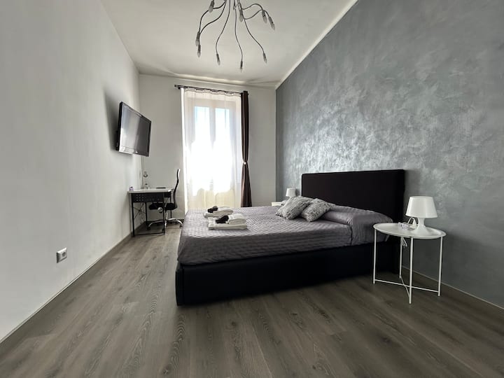 Udobna soba s velikim bračnim krevetom s posteljinom, prostranim ormarom i praktičnim radnim stolom, dizajnirana kako bi osigurala odmor i funkcionalnost.