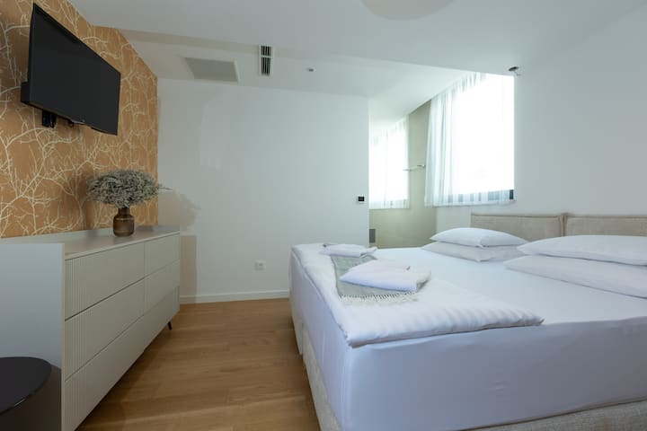 Spacious bedroom with an extra-large double bed, high-comfort mattress, cozy lighting, a dressing table, private bathroom, wardrobe – perfect for peaceful moments.