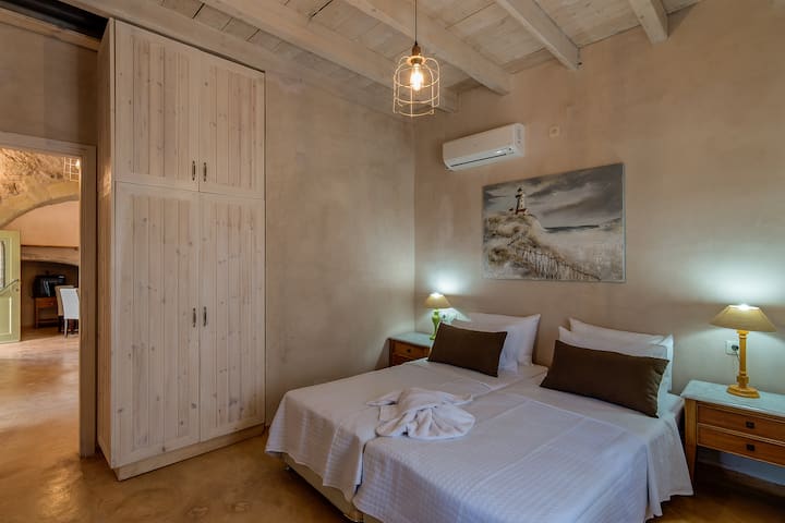 Спалня с 2 отделни легла на приземния етаж, оборудвана с климатик, предлагаща комфорт и зашеметяваща гледка към морето през прозорците си - идеална за спокоен и освежаващ престой!