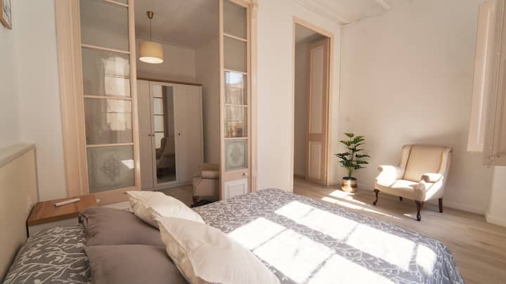 ห้องนอนสไตล์ห้องสวีทขนาดใหญ่พร้อมห้องแต่งตัวขนาดใหญ่และระเบียงกลางแจ้งที่มองเห็นถนน