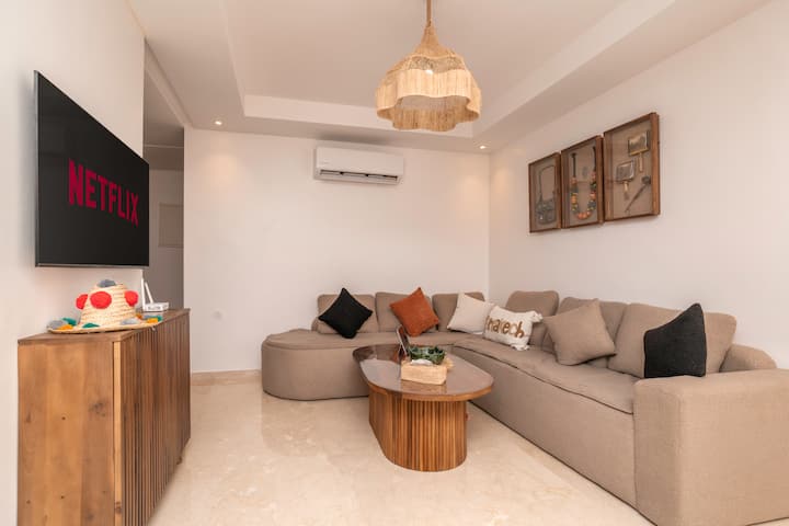 Sebule yenye nafasi kubwa na angavu inakukaribisha katika mazingira ya joto na ya kisasa, yanayofaa kwa ajili ya kupumzika au kushiriki wakati wa kirafiki.