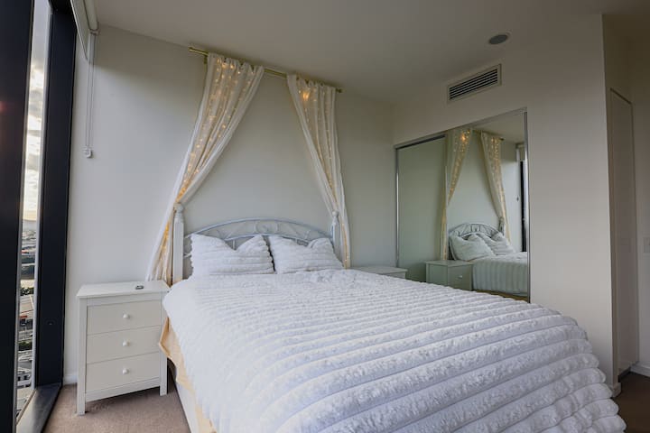 غرفة نوم جميلة ومليئة بالضوء الطبيعي، تتميز بسرير متوسط الحجم.
نوافذ ممتدة من الأرض إلى السقف مع إطلالات شاملة على ويست إند وساوث بريسبان.
خزانة ملابس مدمجة وديكور عصري ومريح.