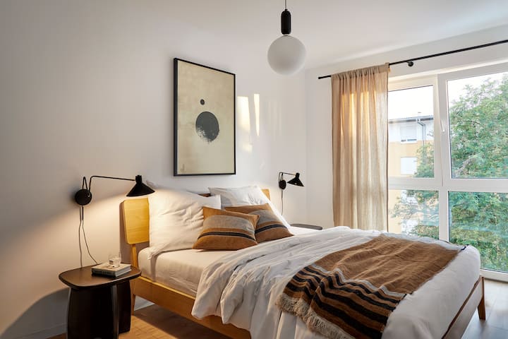 Svetlá spálňa s útulnou manželskou posteľou veľkosti King, štýlovými detailmi a veľkými oknami – ideálne miesto na pokojné noci.