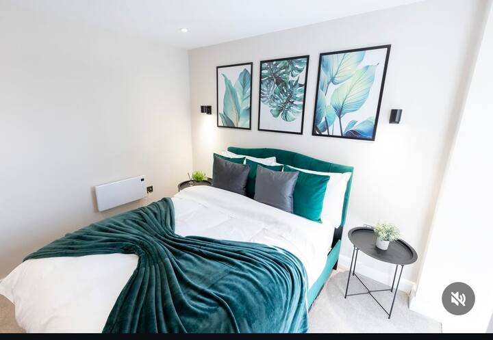 غرفة نوم عصرية ومريحة مع سرير مزدوج فخم، وفن نباتي على الحائط، وإضاءة ناعمة، وجماليات مشرقة ونظيفة.