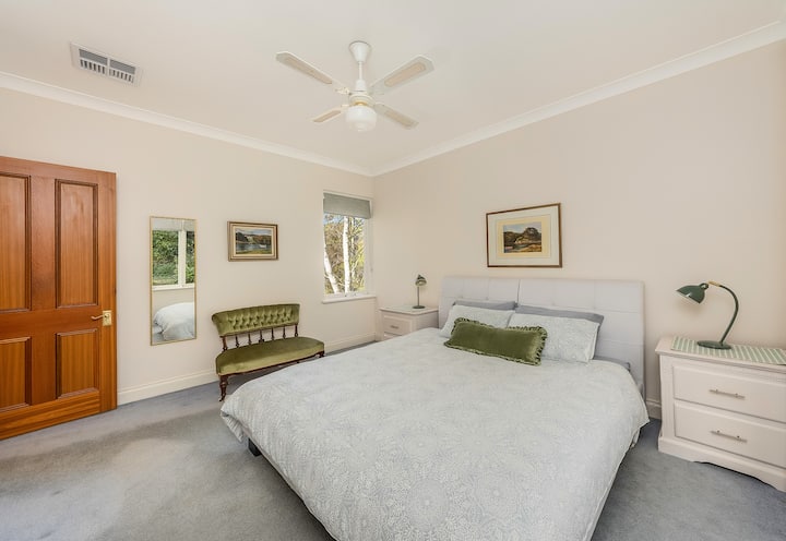 Bedroom 1 with luxurious king bed, quality bed linen, ensuite bathroom, ceiling fan, ducted air conditioning, and beautiful views of the garden and vines