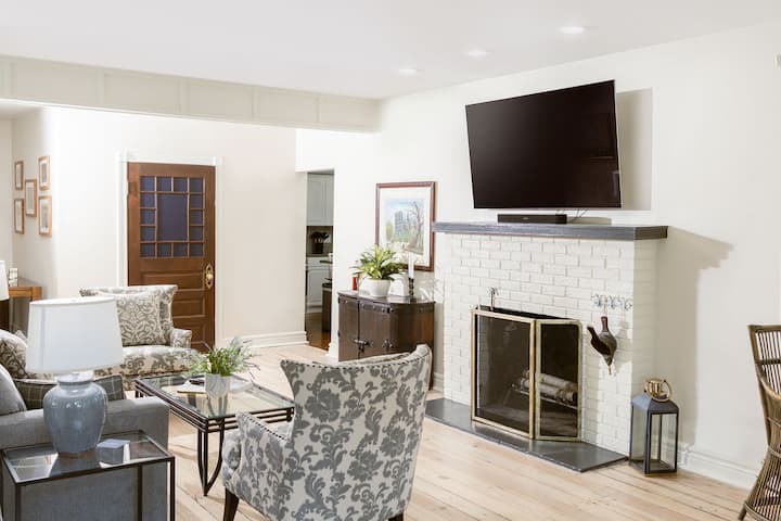 Bright, inviting space with comfortable couches and chairs, a cozy fireplace, and a smart TV for relaxing evenings. Open layout connects seamlessly to the dining room and sunroom, making it perfect for gathering with family and friends.