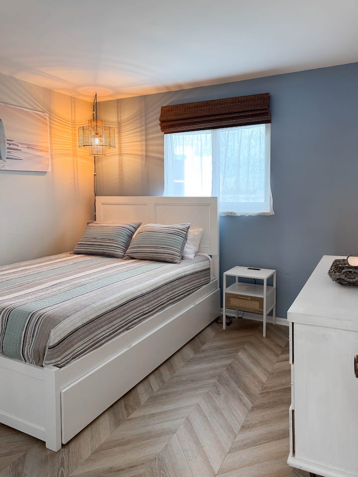 Guest bedroom with a queen bed, twin XL trundle, Firestick streaming TV, pack ’n play, and high chair stored in the closet.