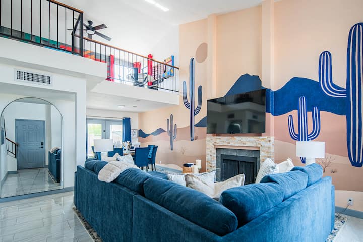 Oddýchnite si v jasnom, otvorenom priestore s odvážnou nástennou maľbou kaktusu, pohodlnou modrou sedacou súpravou, inteligentným televízorom a útulným krbom – ideálne na oddych po dni strávenom vonku.
