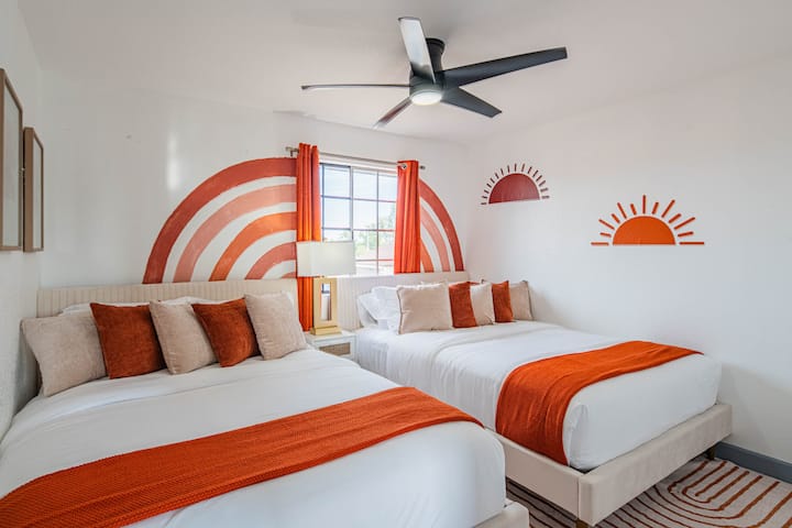 Jasná, zábavná a plná slnečného svitu – táto izba na poschodí má dve manželské postele, hravé nástenné umenie inšpirované západom slnka a odvážne oranžové akcenty, ktoré oživujú atmosféru púšte.