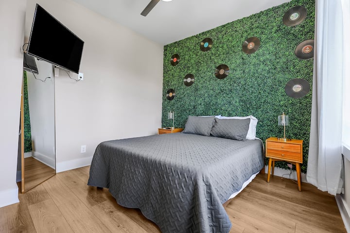 Music-themed bedroom with cozy bedding, vinyl record decor, and a mounted TV—perfect for relaxing after a night out in Nashville.