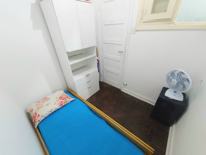 חדר שינה עם מאוורר, ארון וחלונות גדולים.