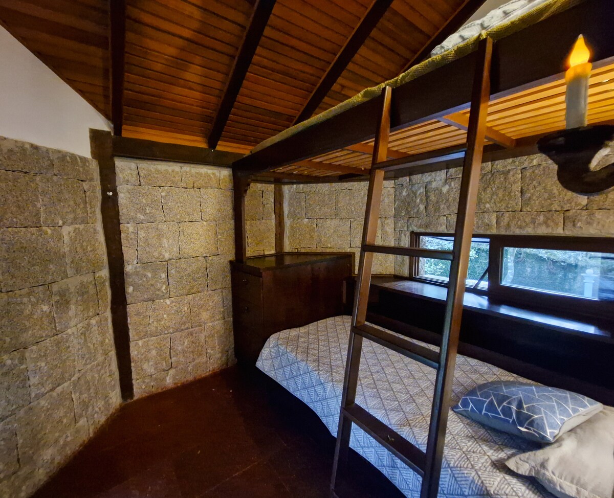 Habitación para dos personas, con litera equipada con cómodas y cajones incorporados. Tiene un estante con perchas para organizar la ropa y una hermosa vista del bosque, lo que aporta comodidad, practicidad y contacto con la naturaleza en un solo espacio.