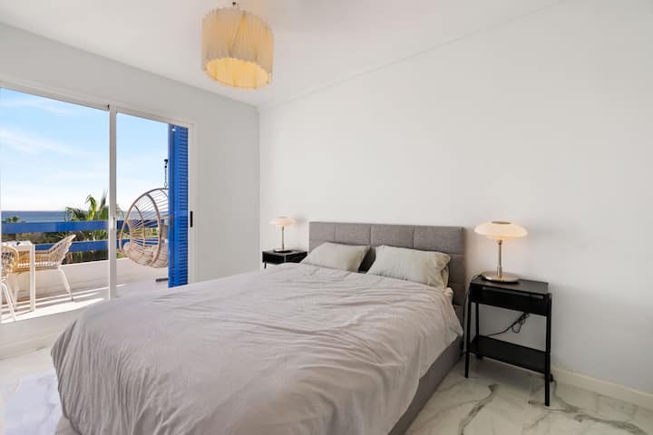 Tritt ein in ein geräumiges Hauptschlafzimmer mit einer Verbindungstür aus Glas, die sich zu einem privaten Balkon mit atemberaubendem Meerblick öffnet. Das Zimmer bietet eine ruhige, luftige Atmosphäre, perfekt zum Entspannen mit renoviertem, eigenem Bad.