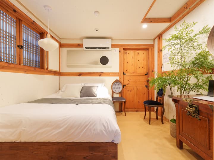 Просторното легло с чисти, пухкави бели завивки и сива копринена пътечка изглежда удобно и релаксиращо. Традиционната хартиена стена има модерна рамка, боядисана с черен порцелан, и климатик. Слънчевата светлина влиза през традиционния дървен прозорец с решетка вляво, а вдясно има тоалетна, когато отворите дървената врата. Има традиционен шкаф и два стола, така че можете да поставите лаптопа си на него и да го използвате като офис пространство, така че това е спалня, която хармонизира традицията и модерната чувствителност.