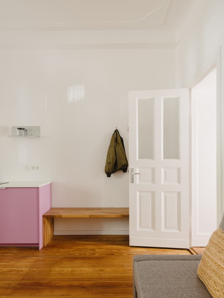 Acceso al salón con banco de madera incorporado y ganchos junto a la cocina