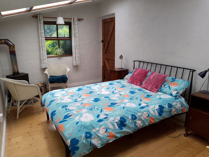 Cama doble completa centrada dentro de la habitación. Puerta de entrada privada a la derecha.