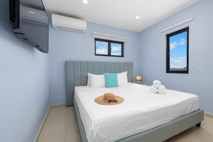 Ეს ჰაეროვანი საძინებელი გთავაზობთ მშვიდ კომფორტს კეთილმოწყობილი საწოლებით, ხრაშუნა თეთრეულითა და სანათით საღამოს რბილი განათებისთვის.