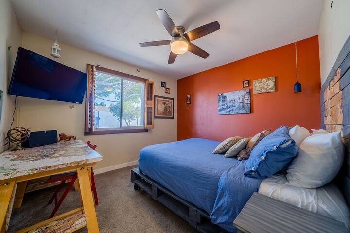 the second bedroom has a travel-themed, queen-size bed, handmade bed frame, and headboard, custom work map desk, ceiling fan, 42" smart tv