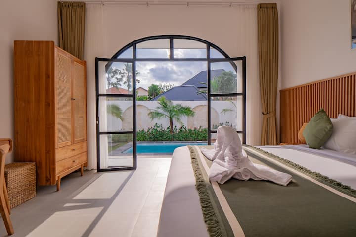 Luxury bedroom with plush bedding and pool views for ultimate relaxation.