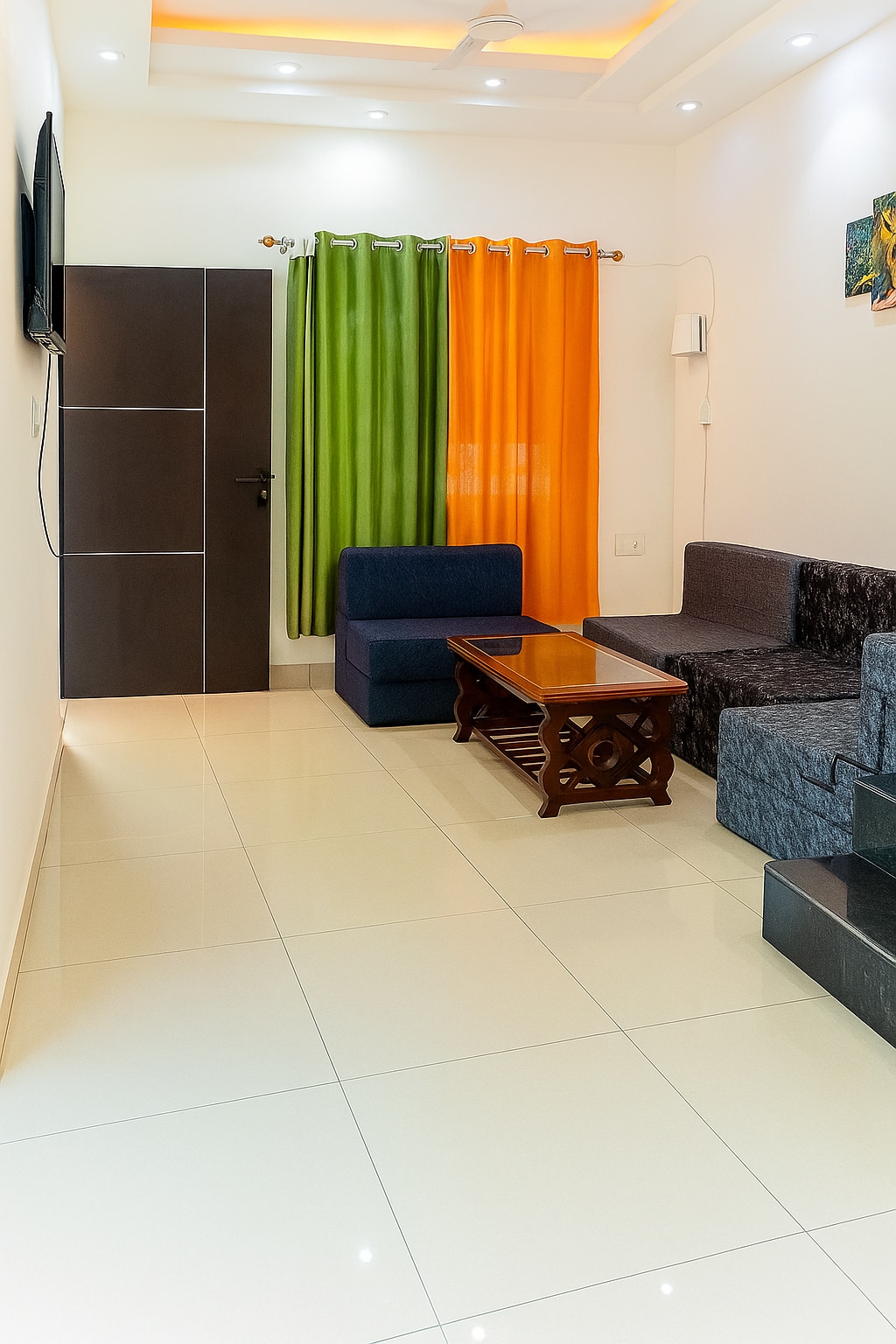 A spacious living area features sleek, glossy tiled flooring. A dark wooden coffee table is centrally placed, surrounded by a blue sofa and a dark-colored sectional couch. Vibrant green and orange curtains frame a window, providing a bright contrast to the neutral walls.