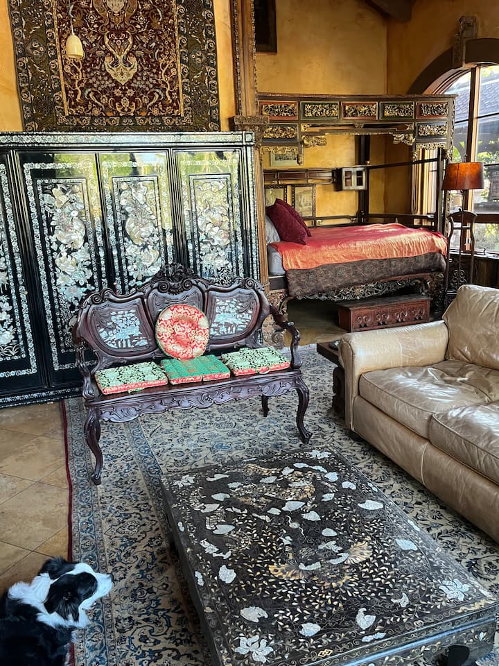 Le Salon Chinois עם מיטת קינג סייז עם חופה, ארון ושולחן מלכה בשחור, חלונות גדולים לאור טבעי עם וילונות האפלה וספה מעור עדינה לצפייה בתוכן בסטרימינג ב-Wi-Fi על מסך 65 אינץ'.