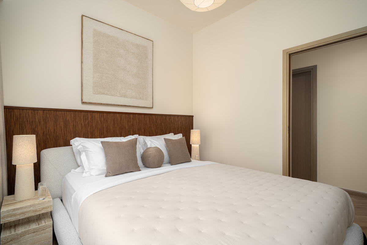 Een stijlvolle slaapkamer met een gezellig bed, modern meubilair en kamerhoge ramen met een adembenemend uitzicht op de stad, zowel overdag als 's nachts.