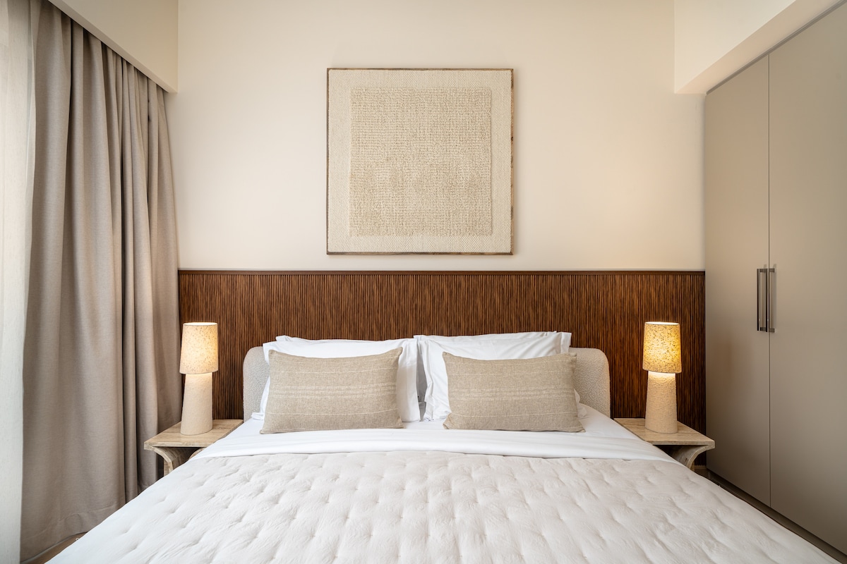 Een stijlvolle slaapkamer met een gezellig bed, modern meubilair en kamerhoge ramen met een adembenemend uitzicht op de stad, zowel overdag als 's nachts.