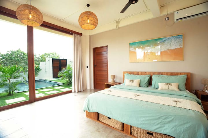 Dieses Schlafzimmer im Erdgeschoss bietet direkten Zugang zum Pool und Garten. Entspanne dich in einem Queensize-Bett, genieße die Klimaanlage und fühle dich durch Glasschiebetüren, die die Außenwelt hereinbringen, mit der Natur verbunden.