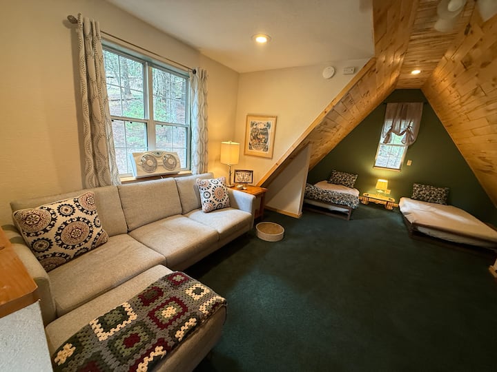 Derde verdieping open loft met woonkamer en twee eenpersoonsbedden.