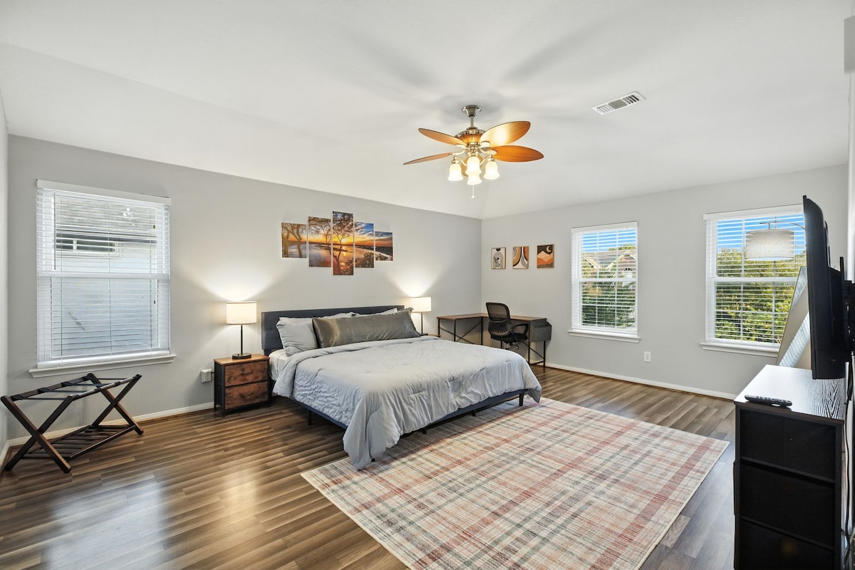 סוויטה ראשית מרווחת עם מיטת קינג סייז, שולחן עבודה, טלוויזיה ואור טבעי.