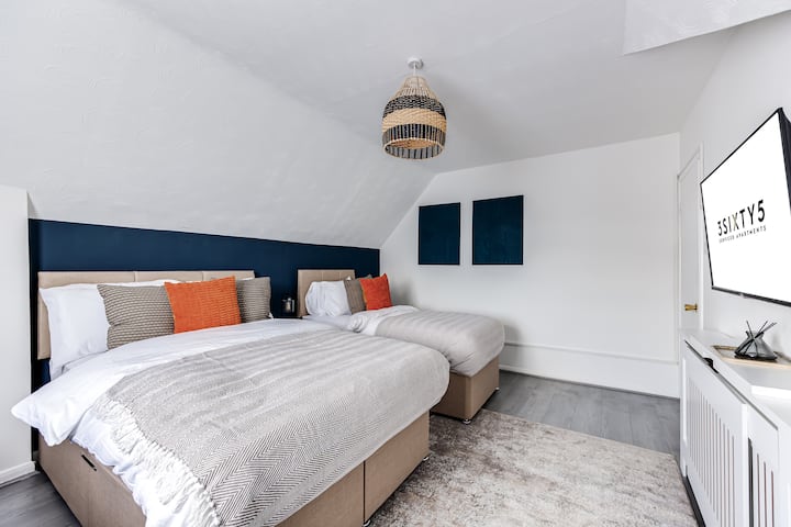 明亮的卧室，配备两张单人床和室内电视娱乐设施。