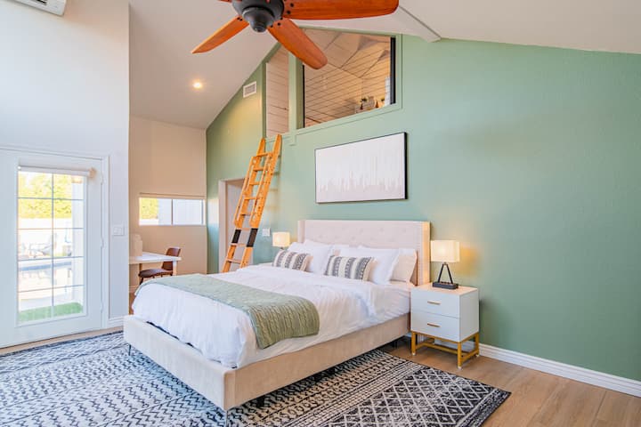 Deze hoofdslaapkamer is iets speciaals. Het is misschien wel mijn favoriete plek in het huis! Tussen de saliegroene accentmuur, de schattige kantoorruimte, de openslaande deuren die openen naar het zwembad en de bonusloftruimte, is het echt uniek!