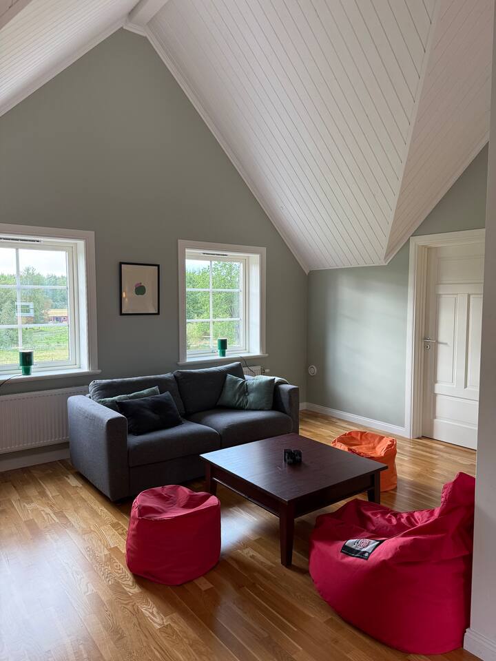 ห้องนั่งเล่นที่อบอุ่นพร้อมเตียงโซฟาและพูฟ – สถานที่ที่น่าอยู่สำหรับปาร์ตี้เล่นไพ่หรือเกมกระดาน นอกจากนี้ยังมีพื้นที่สำหรับผู้ที่ต้องการทำงานจากที่บ้านอย่างสงบและเงียบ