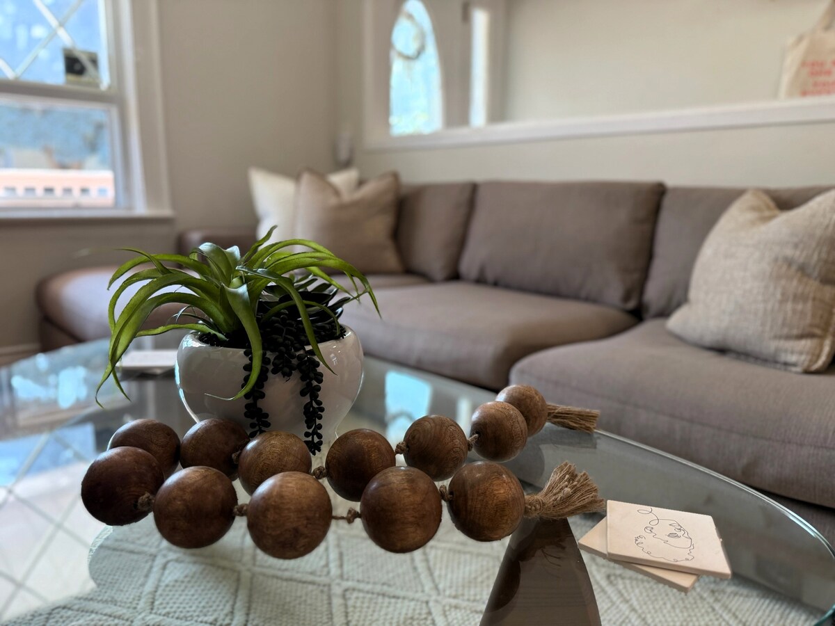 Una acogedora sala familiar con decoración boho, con un cómodo sofá adornado con cojines estampados. El lugar perfecto para que los huéspedes se relajen y tomen una siesta junto a la ventana iluminada por el sol.