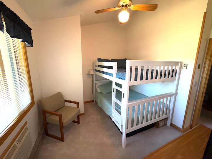 Chumba cha watoto kina vitanda viwili, godoro la sakafuni, kabati, midoli na sehemu ya/c.