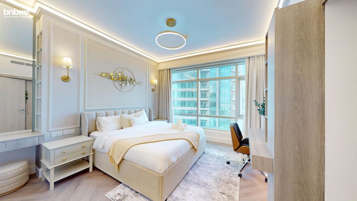 Relájate en un elegante segundo dormitorio con una lujosa cama tamaño king, iluminación suave y una decoración sofisticada. Cuenta con luz solar natural a través de ventanas de suelo a techo, un espacio de trabajo y un almacenamiento moderno, perfecto para estancias prolongadas en Dubái.